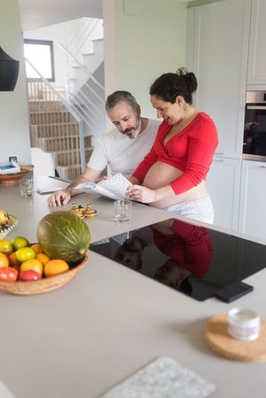 Pregnant woman and male partner deciding what to cook from book