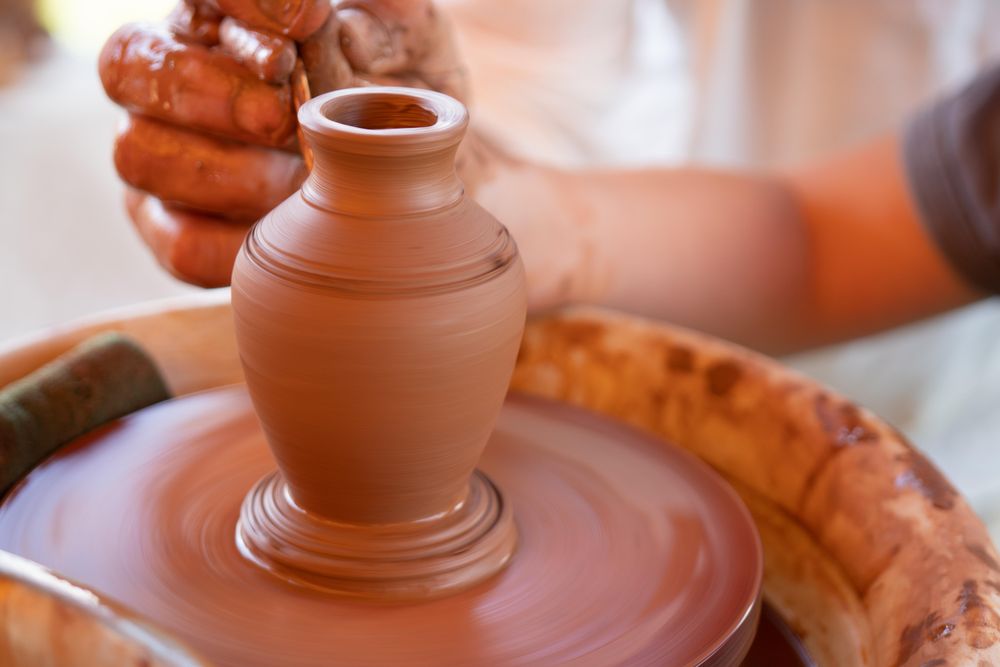 Person making clay pot on round table during daytime
