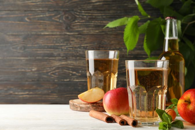 Composition with cider, cinnamon and apples on wooden background