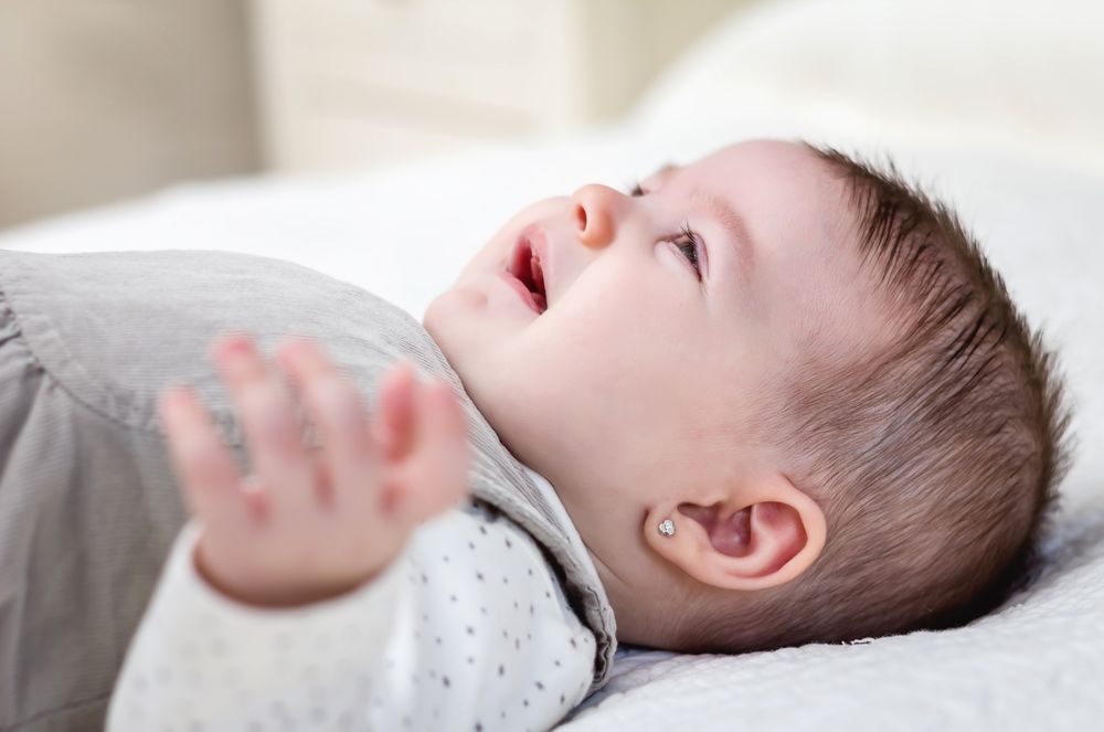 Baby girl crying over white bedcover