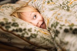 Blond child peeking over a blanket