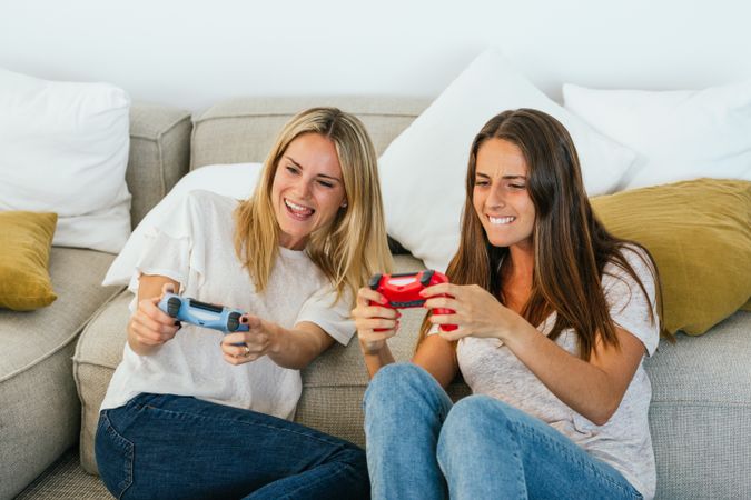 Cheerful women playing videogame on couch