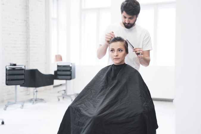 Hairdresser cuts woman's hair with scissors