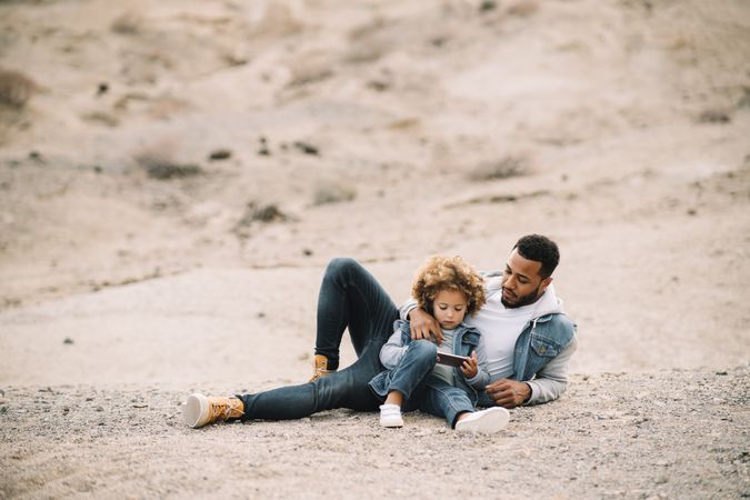 Black father relaxing in nature with ethnic kid