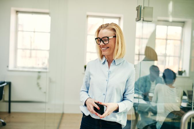 Portrait of blonde woman with cell phone smiling in an office