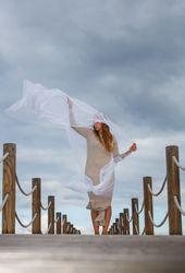 Woman with textile posing in air on footbridge