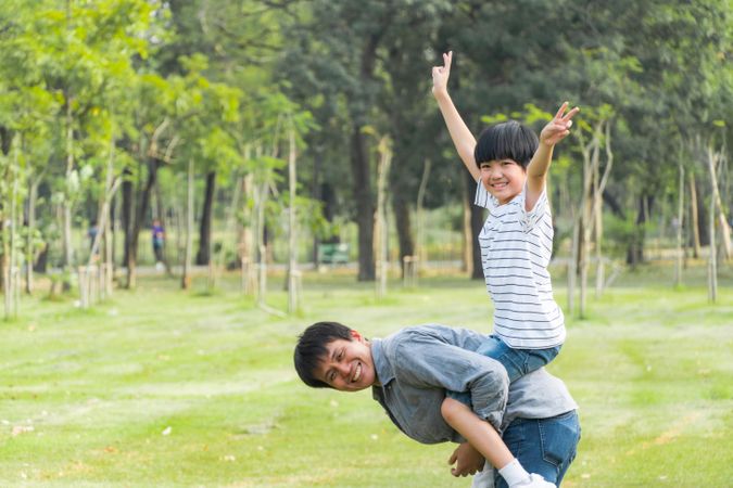 Boy raising arms up in the air on his father’s back