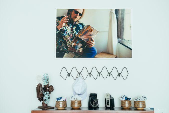 Photo print hanging on wall above a shelf with vintage cameras and ceramics