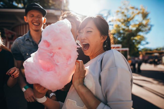 Happy young friends eating cotton candy outdoors
