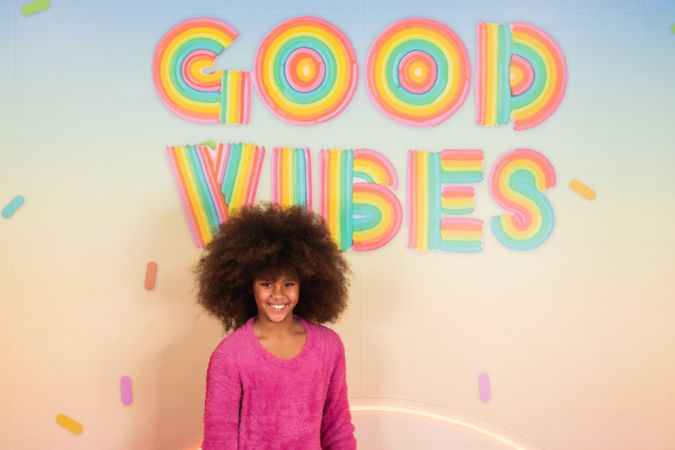 Cheerful Black girl standing in colorful studio