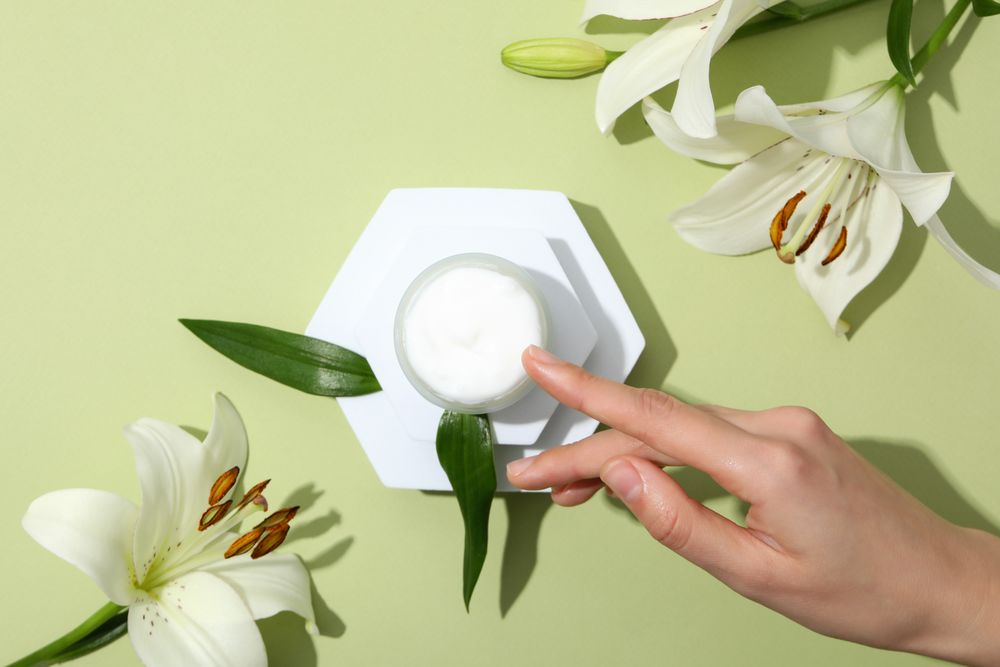 A jar of hand cream with flowers on a light background.