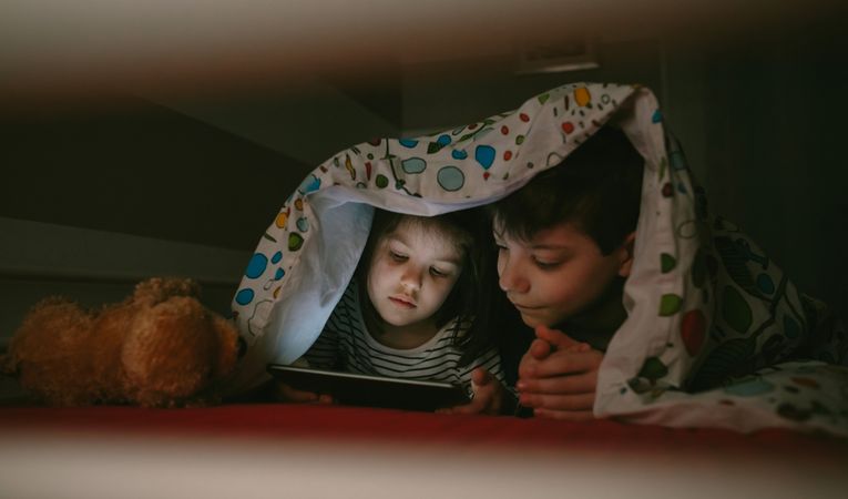 Siblings looking at the tablet in the dark