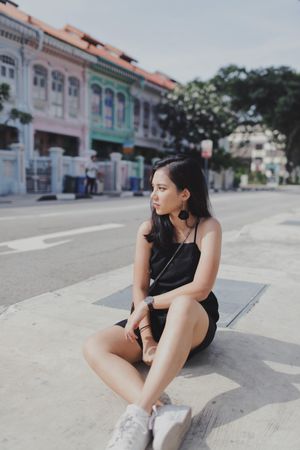 Woman in dark dress sitting on the street