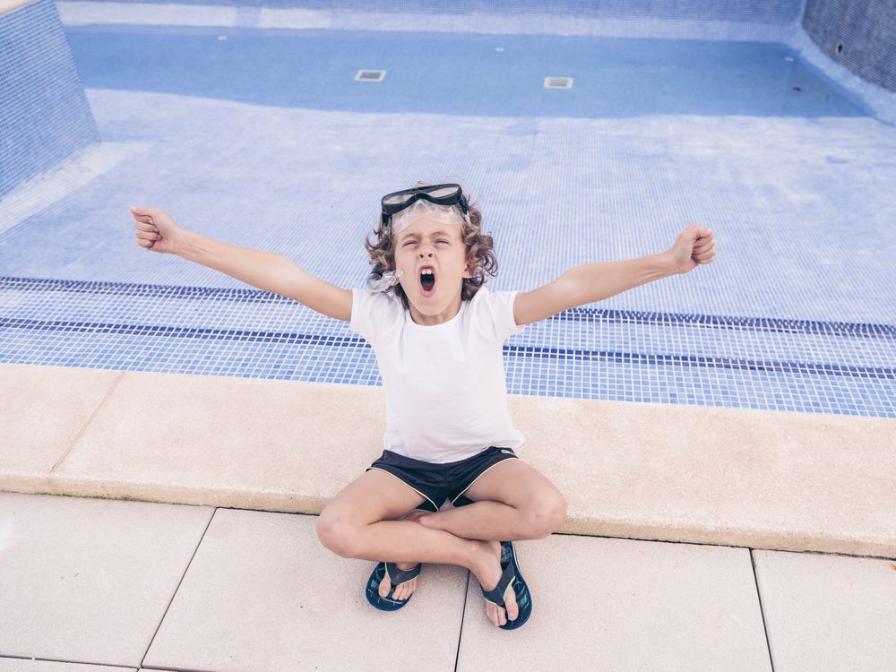 Child in snorkel goggles yawning on poolside