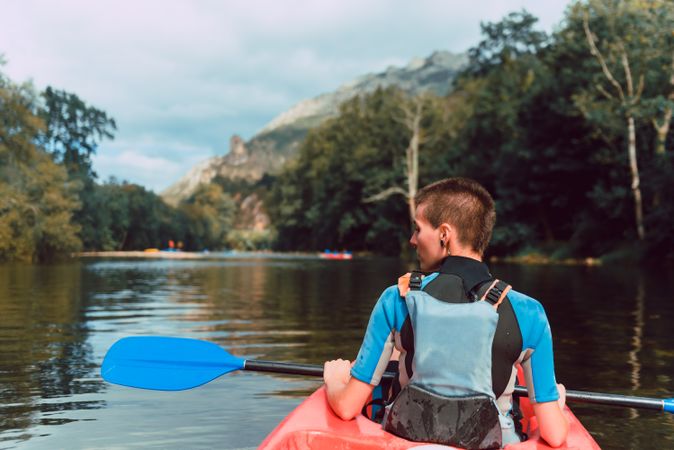 Female kayaking with paddle in raised hands