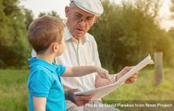Older man with boy reading a newspaper outdoors 42aGe5