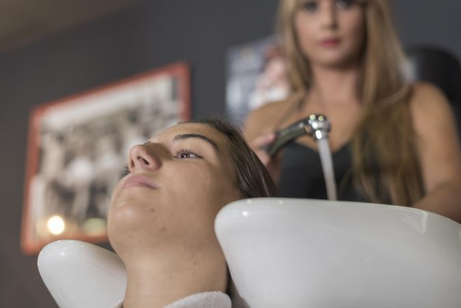 Female with head back in sink at hairdressers having her hair washed