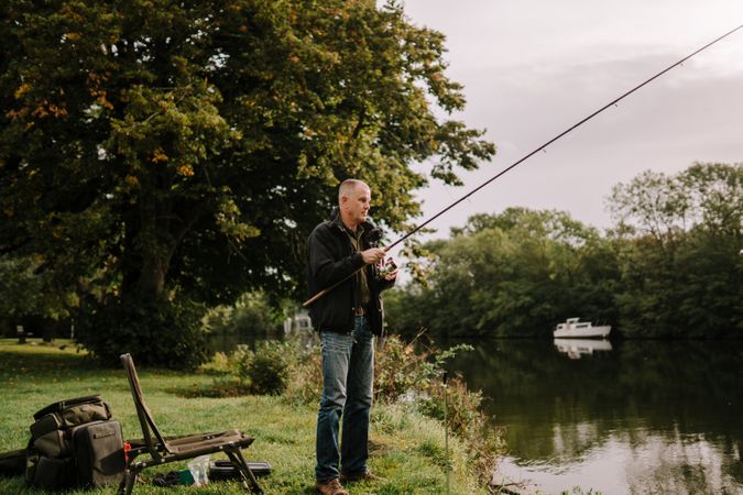 Happy man standing and fishing by river