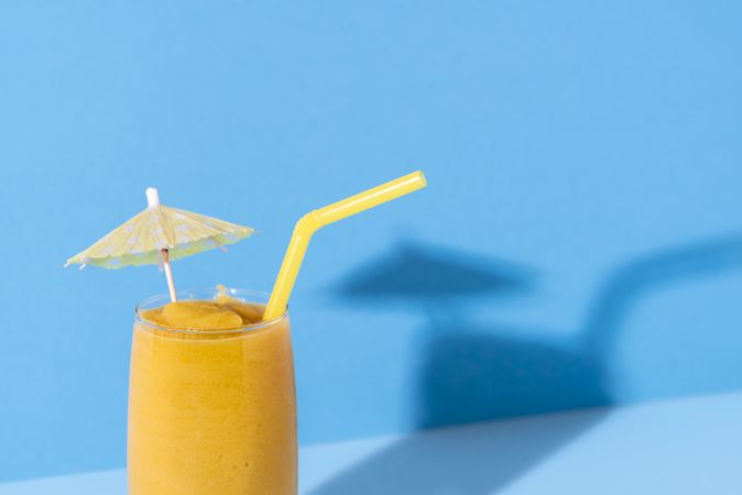 Yellow smoothie with a cocktail umbrella