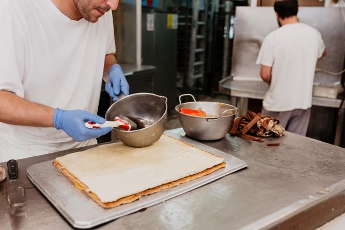 Crop confectioner smearing jam on croissant
