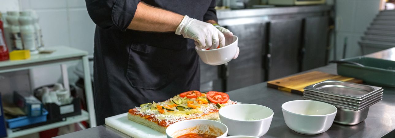 Unrecognizable chef preparing vegetarian focaccia with healthy ingredients in a restaurant kitchen
