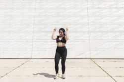 A young woman, dancing and moving, happy, while listening to music with headphones and disconnecting, to relax, after exercising