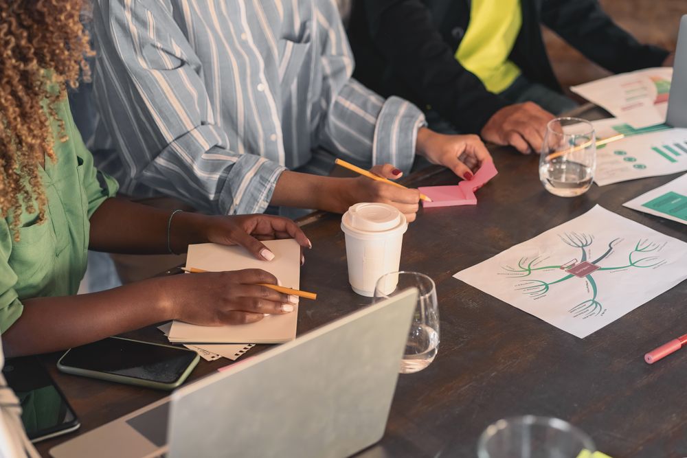 A group of professionals gather around a table, in a brainstorming session