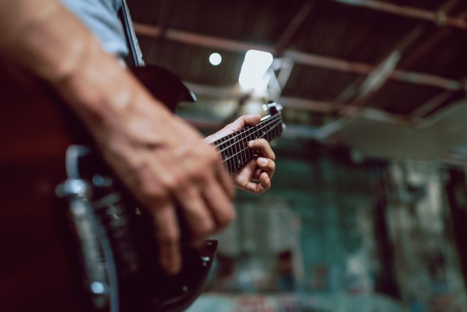 Man clamping strings on guitar neck