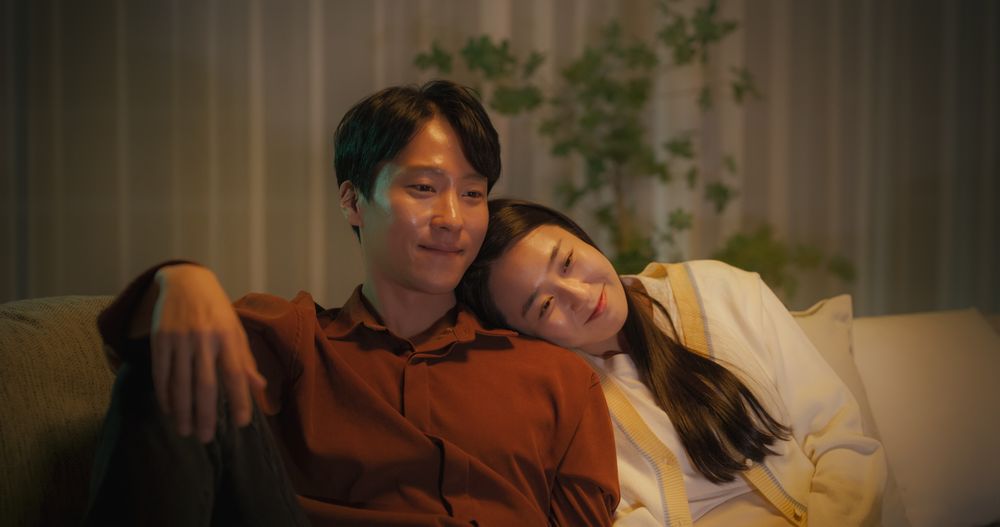 Young Asian Couple Watching a Movie on an Online Streaming Service while Sitting on a Couch at Home.