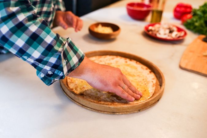 Cropped image of person kneading dough on wooden tray