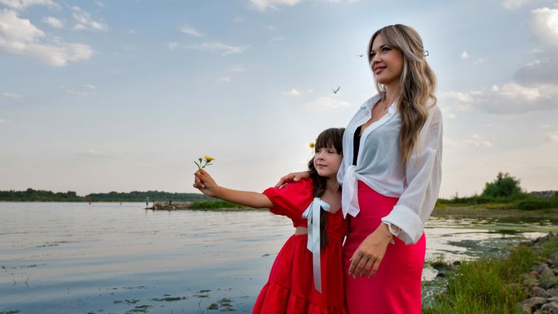 Mom and little daughter walking by the lake or pond