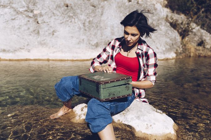 Woman with picnic case on rock in water