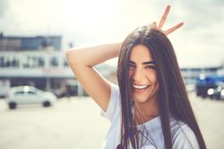 Woman joking making rabbit ears behind her own head