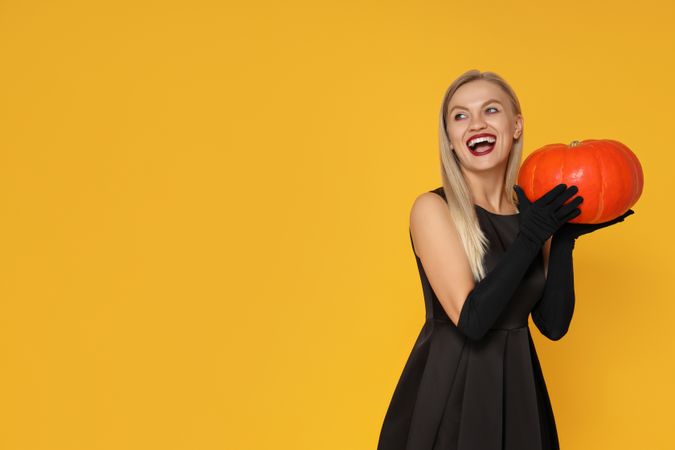 A woman in a Halloween costume with a pumpkin in her hands