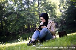 Middle Eastern woman engrossed in a book in the park 5wydWb