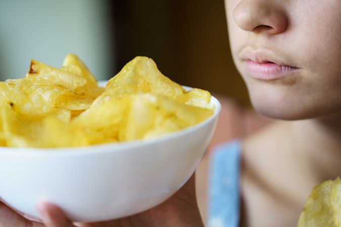 Crop anonymous girl holding bowl full of potato chips