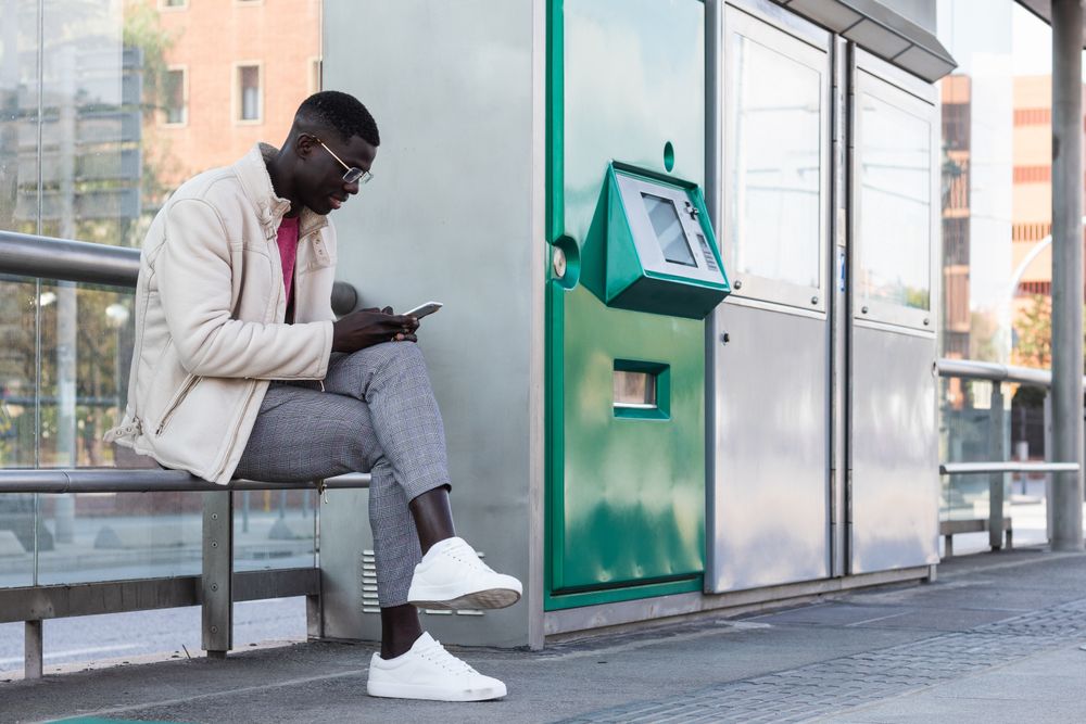 Black male entrepreneur browsing smartphone on train platform