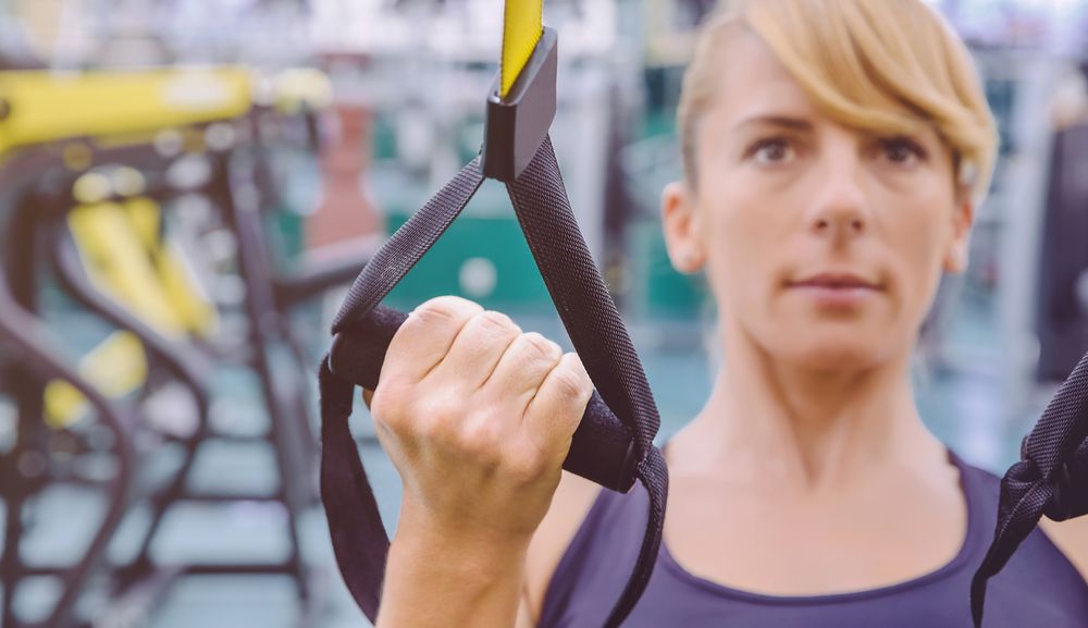 Close up of woman doing upper body exercise with suspension ropes