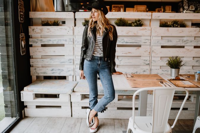 Casual stylish woman standing at table in cafe