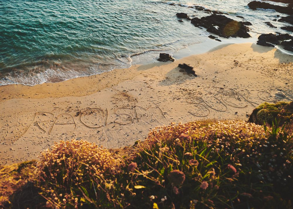 “Racism Sucks” written in the sand