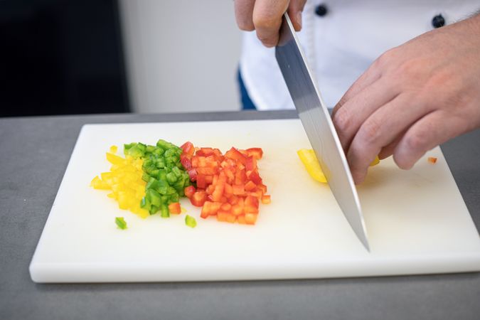 Cook slicing peppers finely on board