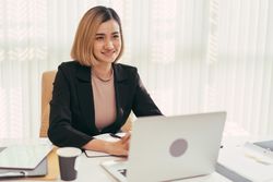 Woman smiling from behind her laptop