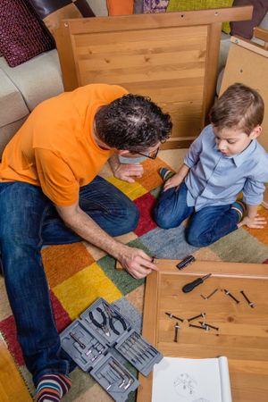 Father and son assembling a new furniture for home