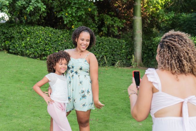 Young mother taking a cell phone photo of her daughters outdoors