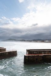 Rock breakwater with raging sea on cloudy weather