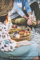 Two people at summer picnic as man opens wine 4NYMe5