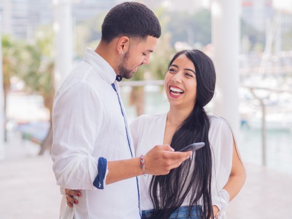 Man messaging on smartphone standing with woman