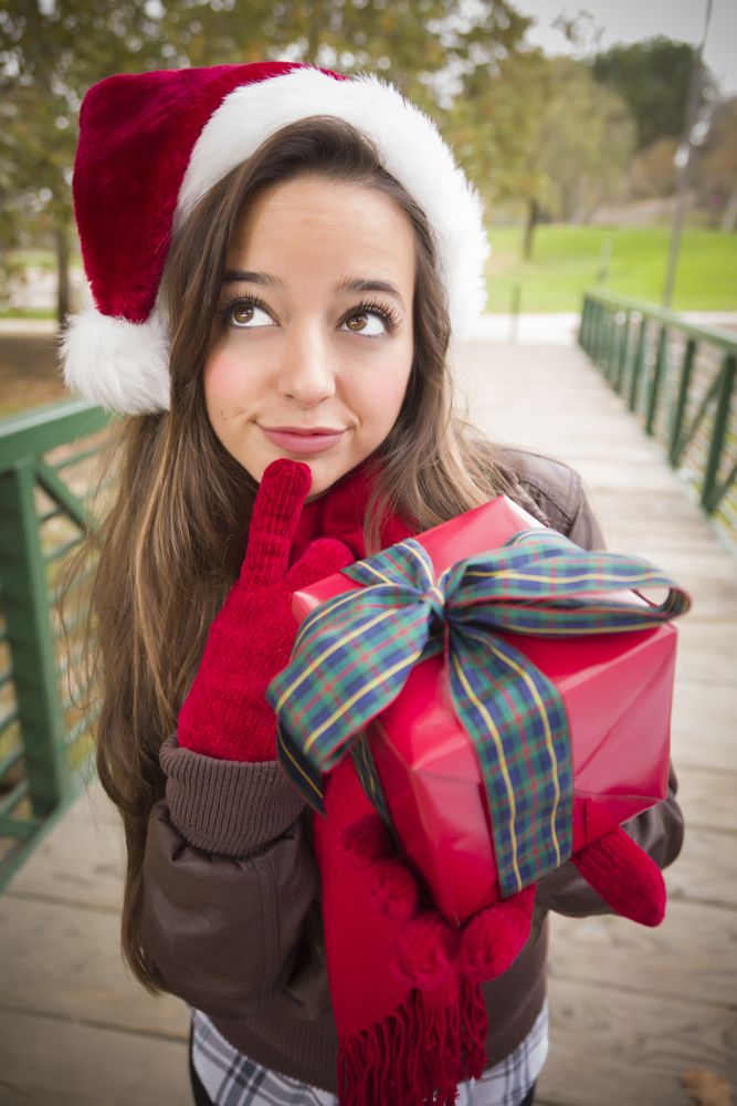 Young Woman Wearing a Santa Hat with Wrapped Gift