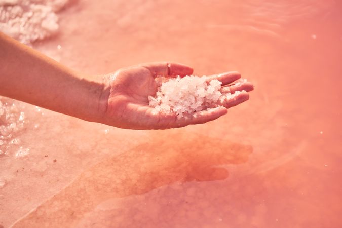 Female holding healing salt pile in pink water