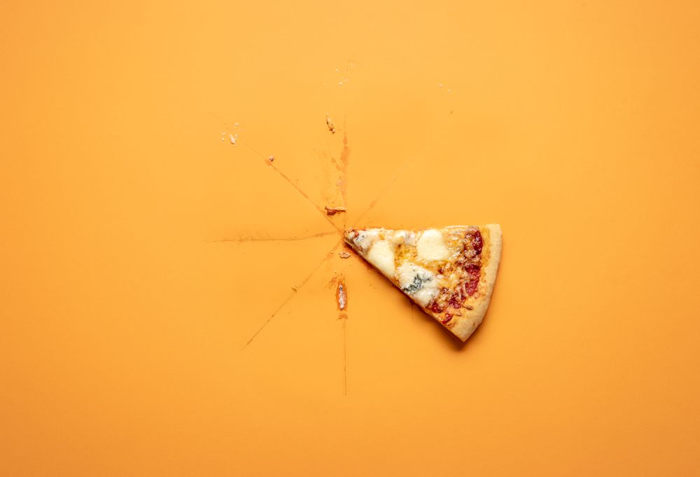 Single pizza slice on orange background